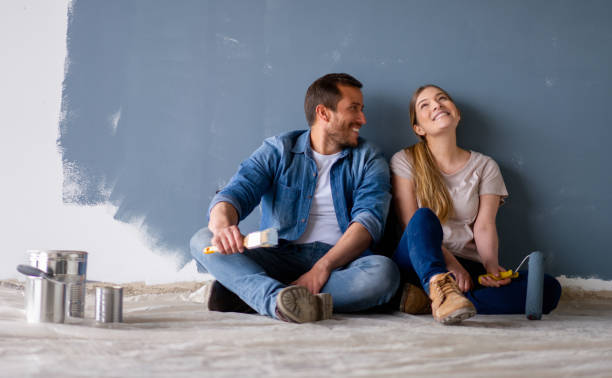 Smiling couple seated before freshly painted wall