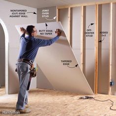 worker putting up a sheet of drywall