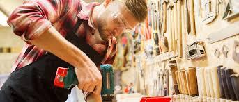 Carpenter using hand heled drill on table top