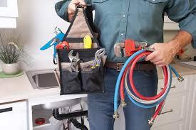 Workman holding tool bag and hoses in left hand