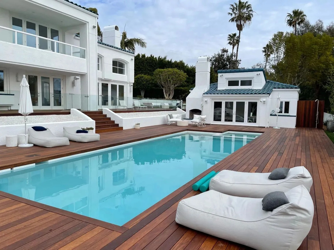 Rectangular pool featuring all wood decking by pool house