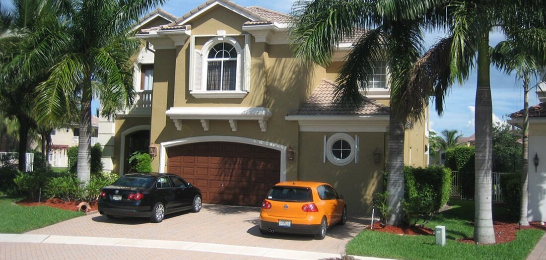 Boca Raton home with two cars in driveway under palm trees