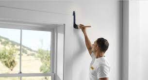 Painter beginning to paint wall by window