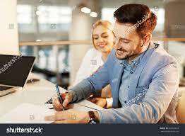 Man signing contract as female looks on