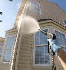 Worker holding high pressure washing gun to clean home's exterior