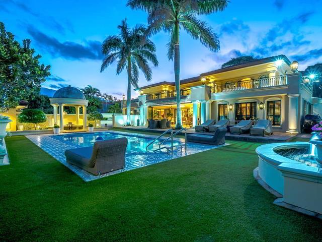 Florida home at dusk featuring pool and manacured lawn