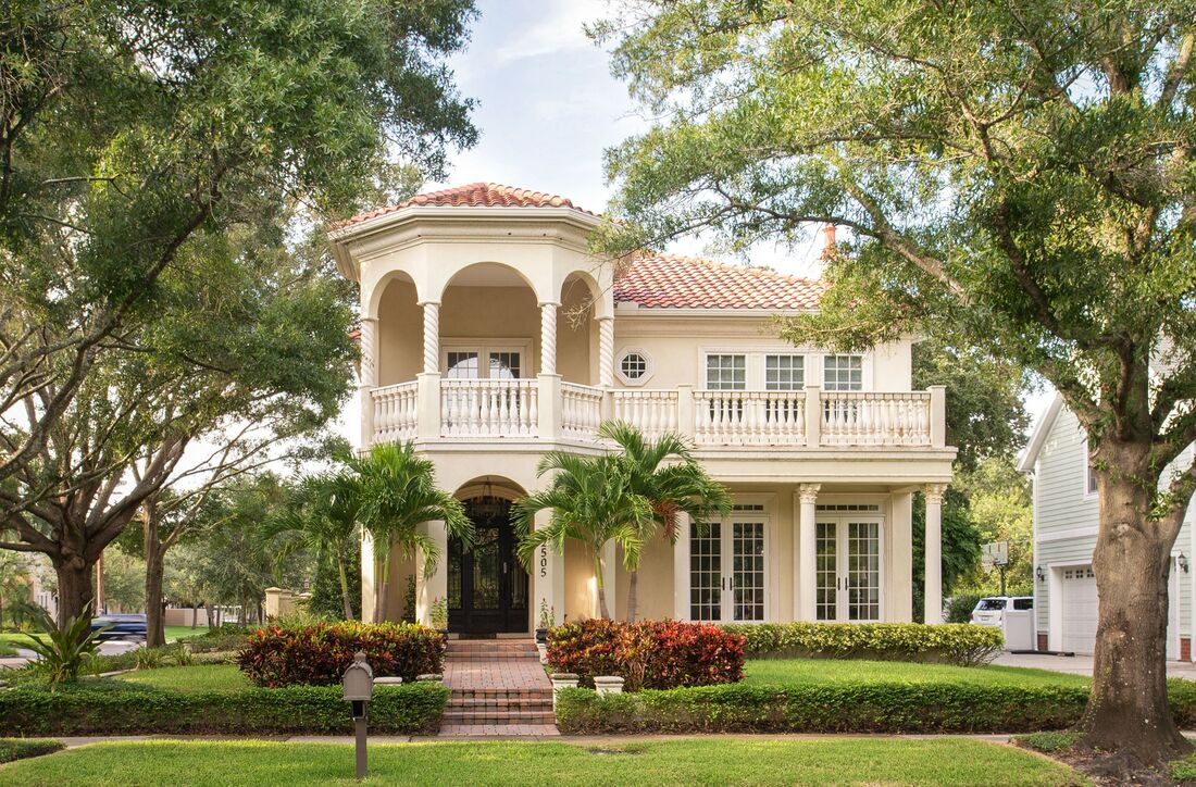 Two story Florida villa surrounded by palm trees and other attractive landscaping